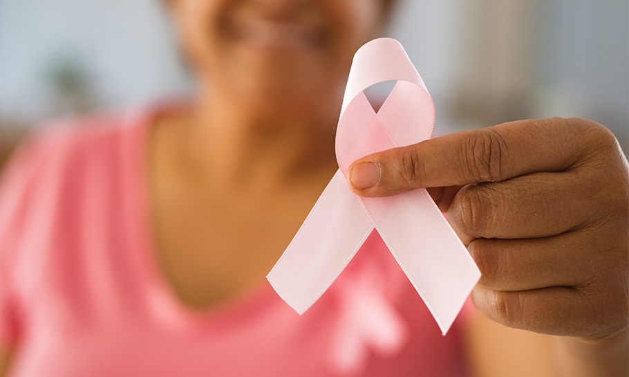 Woman holding up a pink ribbon signifying breast cancer awareness month