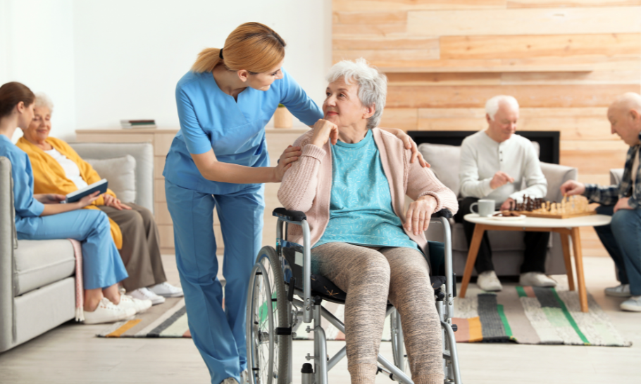 Senior woman in a wheelchair speaking to a nursing home aide.